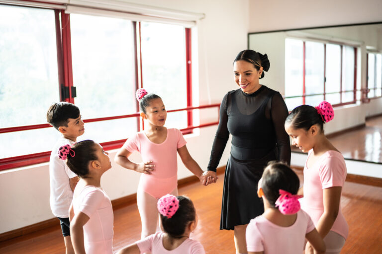 Ballet students holding hands with teacher at dance studio