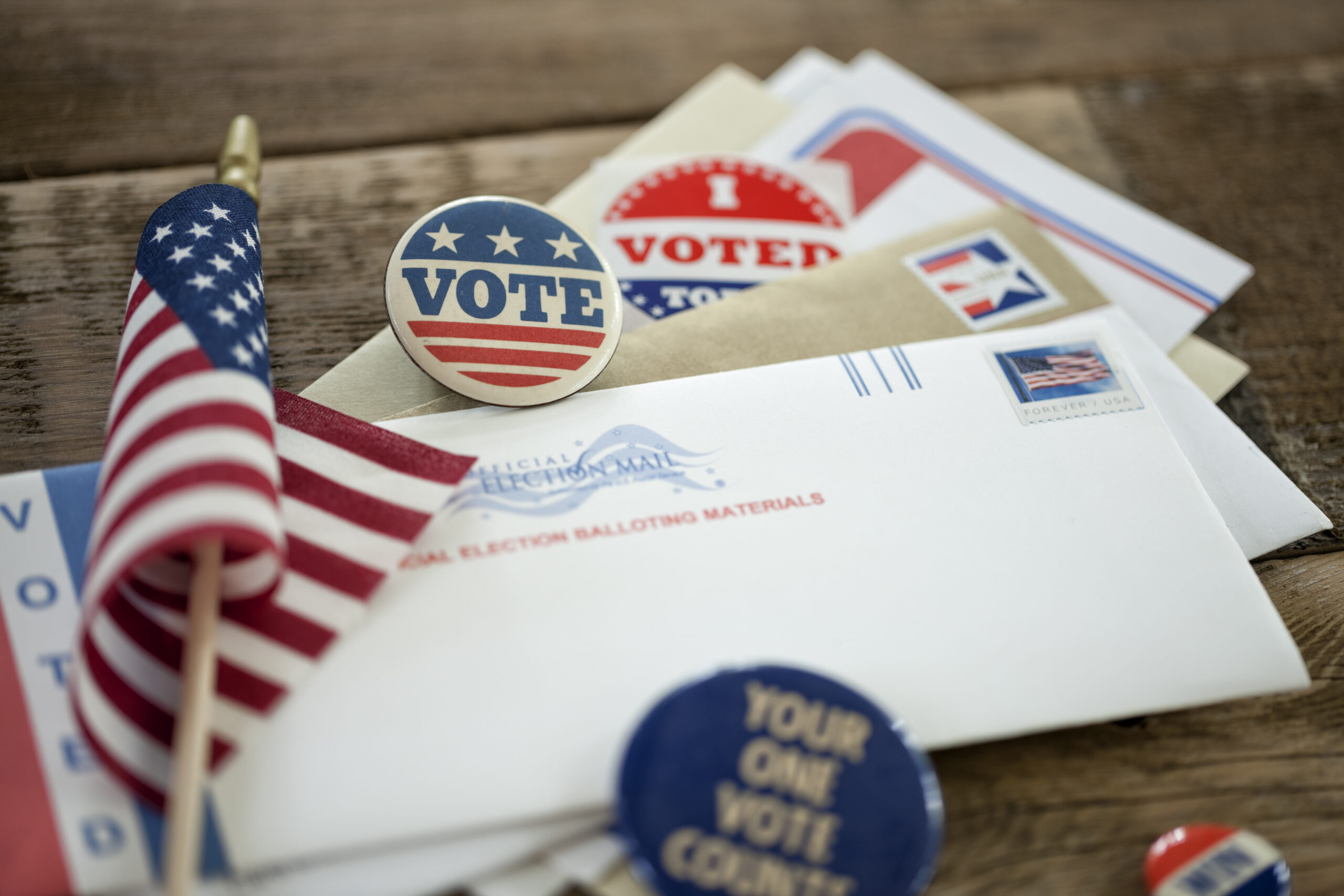 Absentee Ballot and campaign buttons on a wood surface.