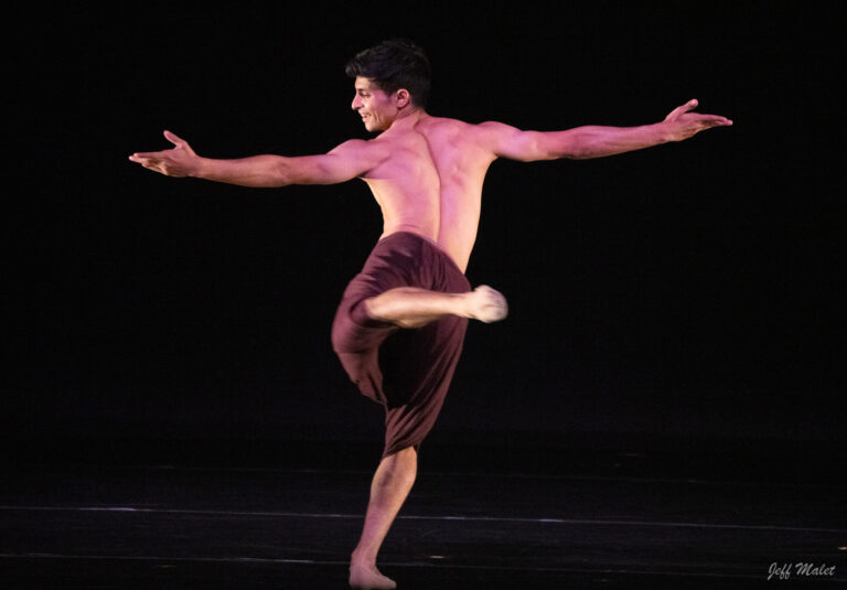 Manish Chauhan with his arms outstretched and his back facing the audience.