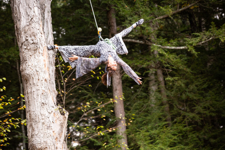 Photo on woman upside down in harness from a tree.