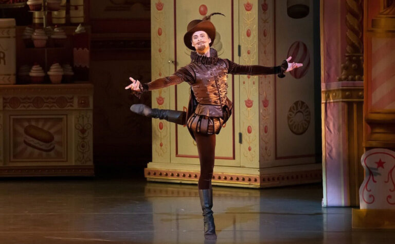 Eric Tamm in performance. He balances in back attitude croisé, arms open and welcoming to the audience.