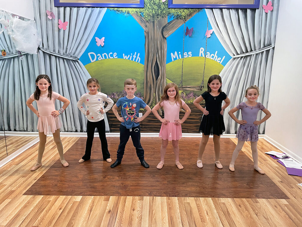 Young students standing in a line in a dance studio.