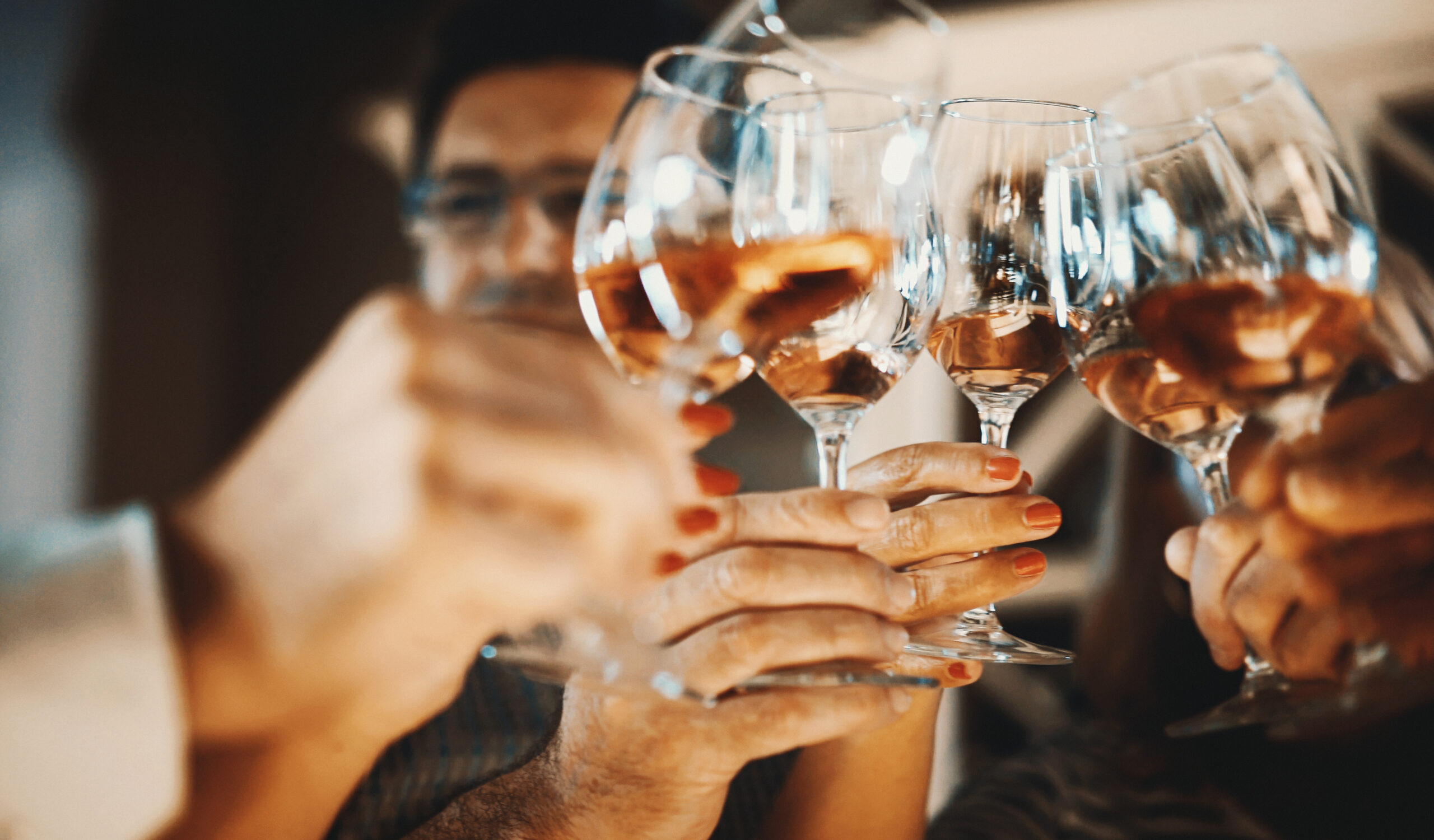 Closeup low angle view of group of unrecognizable people toasting with wine.