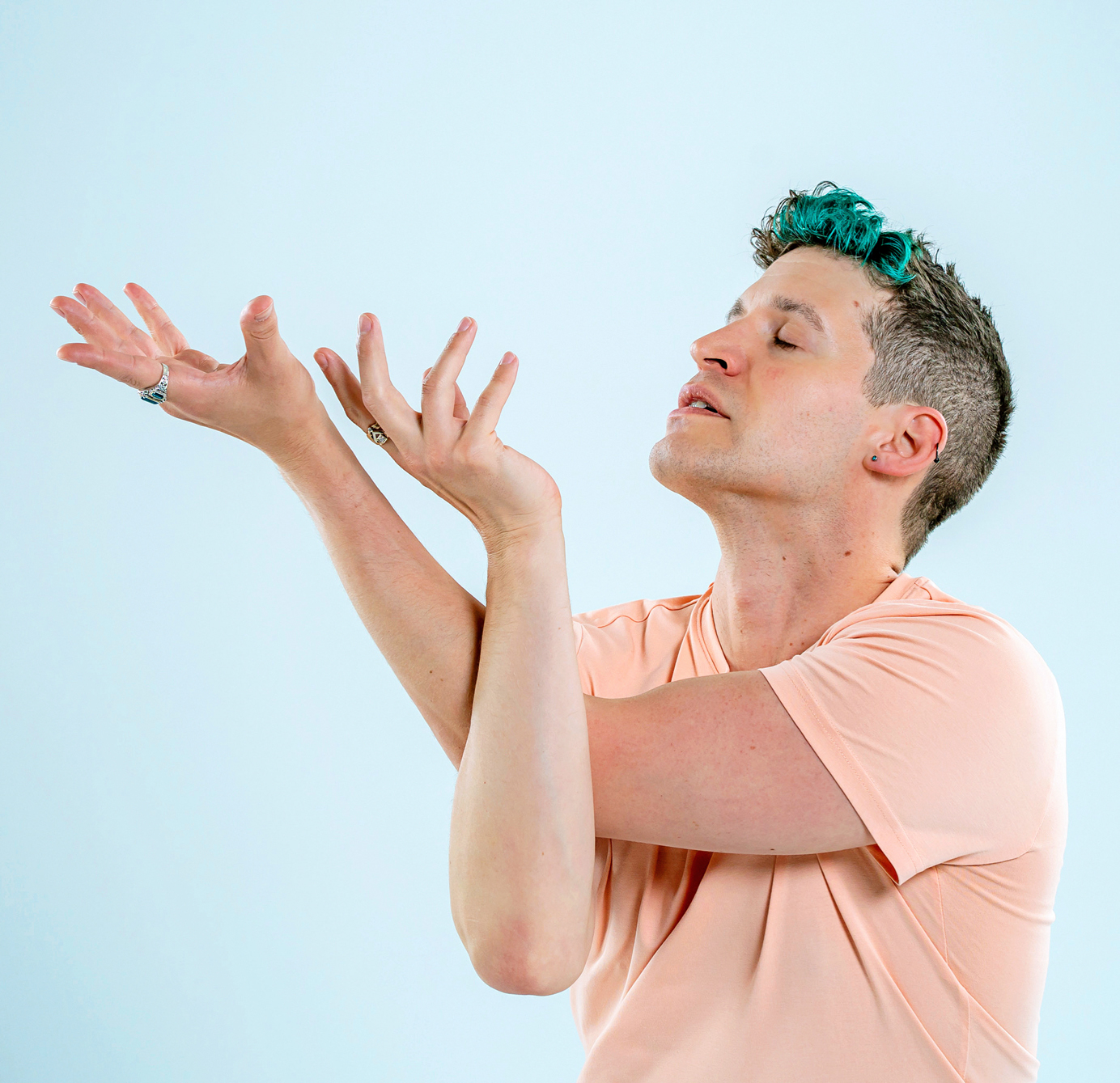 Barry Kerollis in a peach tshirt with his arms folded in type of eagle pose looking upward.