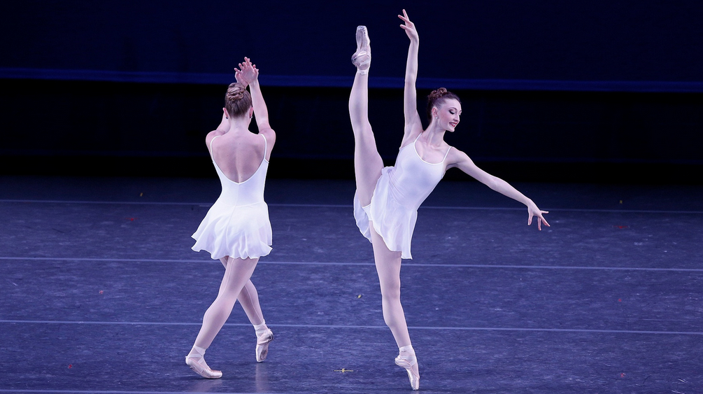 Julia Cinquemani (right) in George Balanchine’s Concerto Barocco at Los Angeles Ballet. She wears a white costume and is positioned next to another dancer dressed in a white dress.