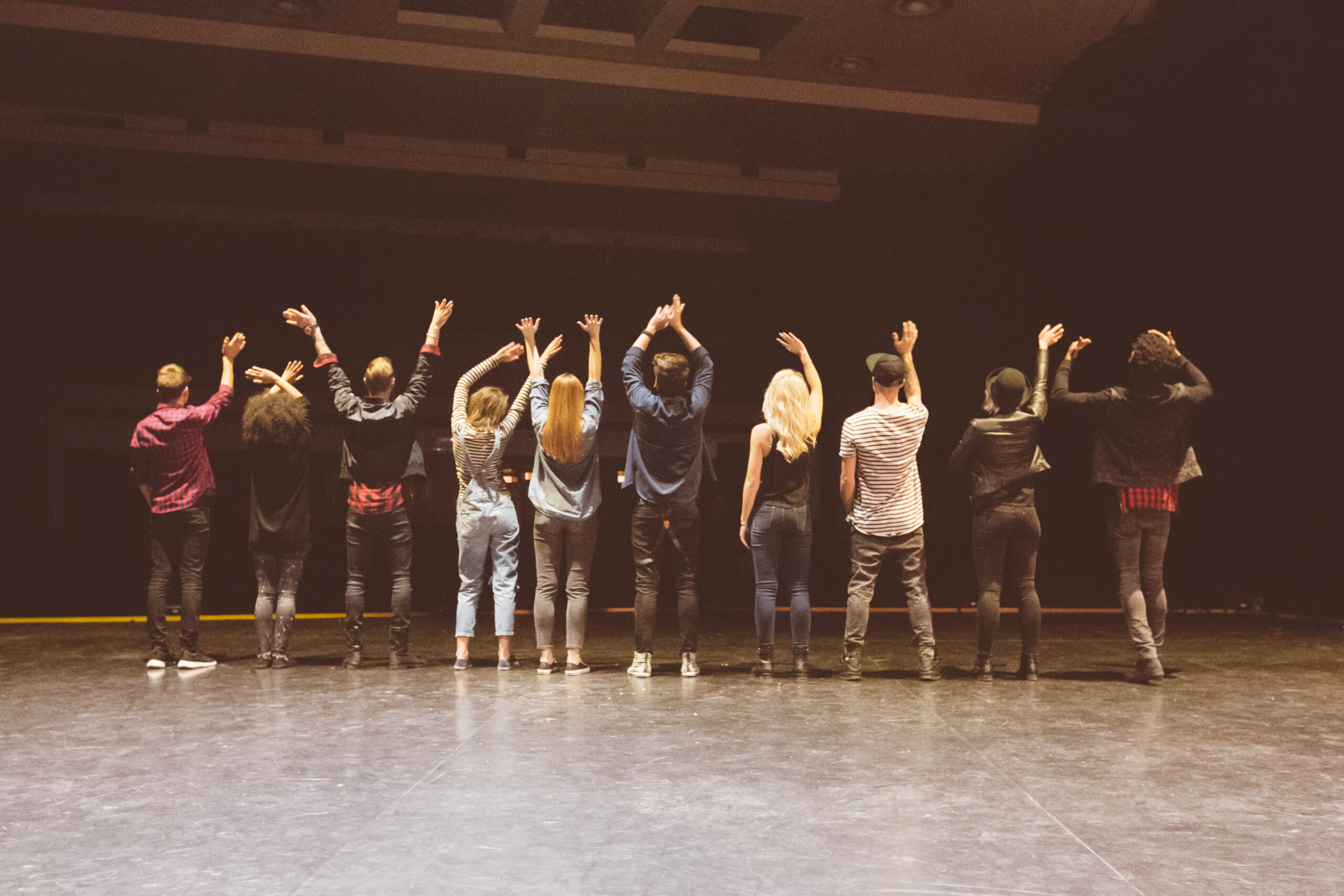 Back view of group of young performers on the stage standing in the line.