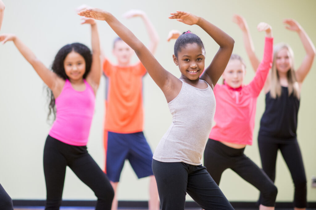 A diverse group of children learning choreography in a dance class.