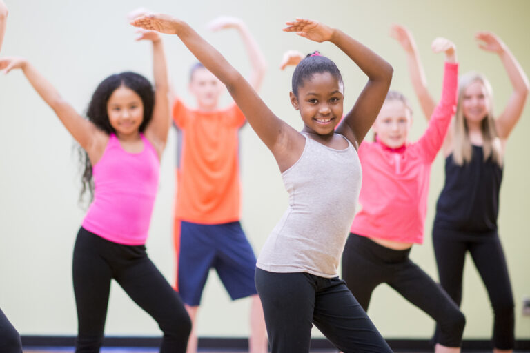 A diverse group of children learning choreography in a dance class.