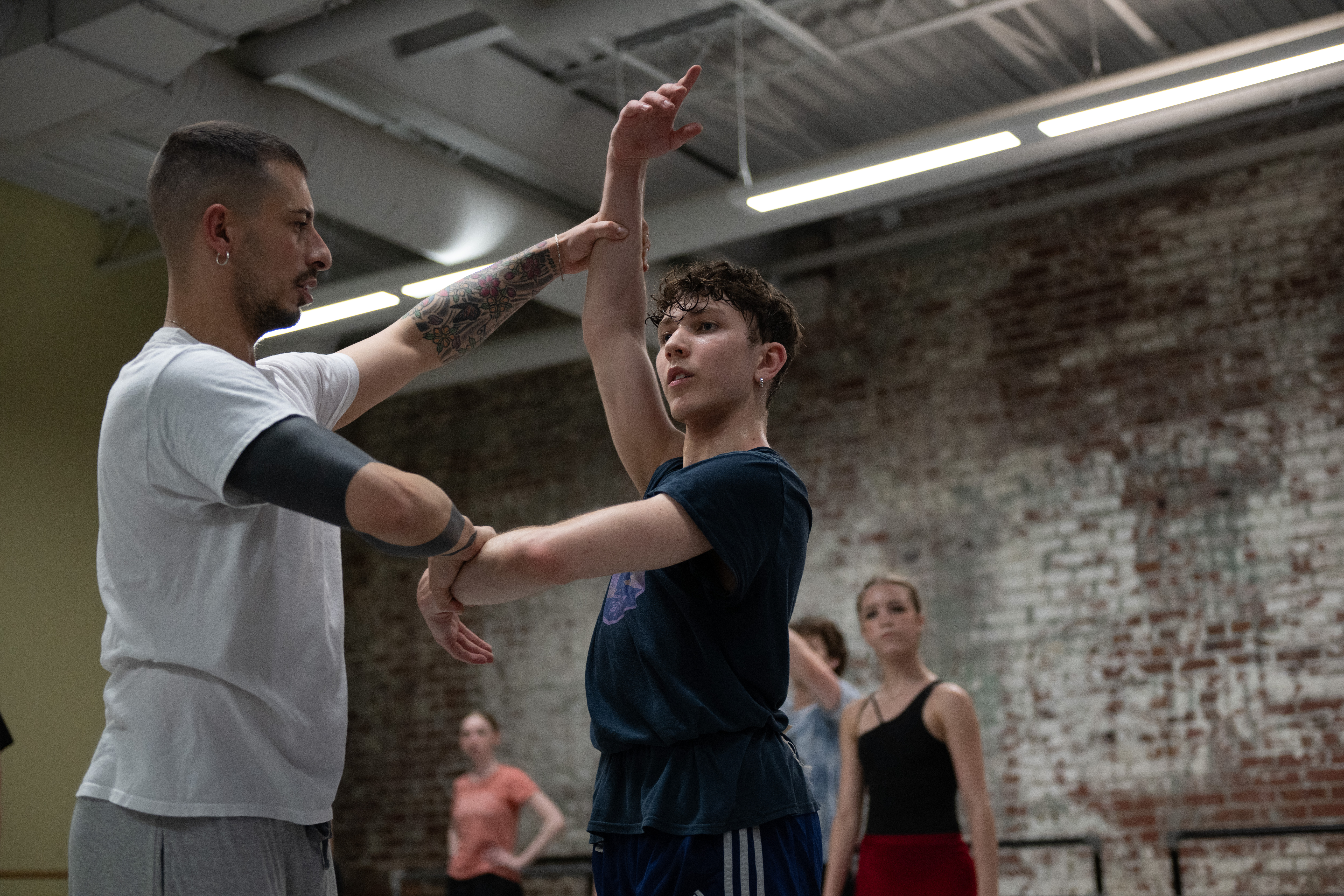 A dance instructor positioning a students arms in the center.