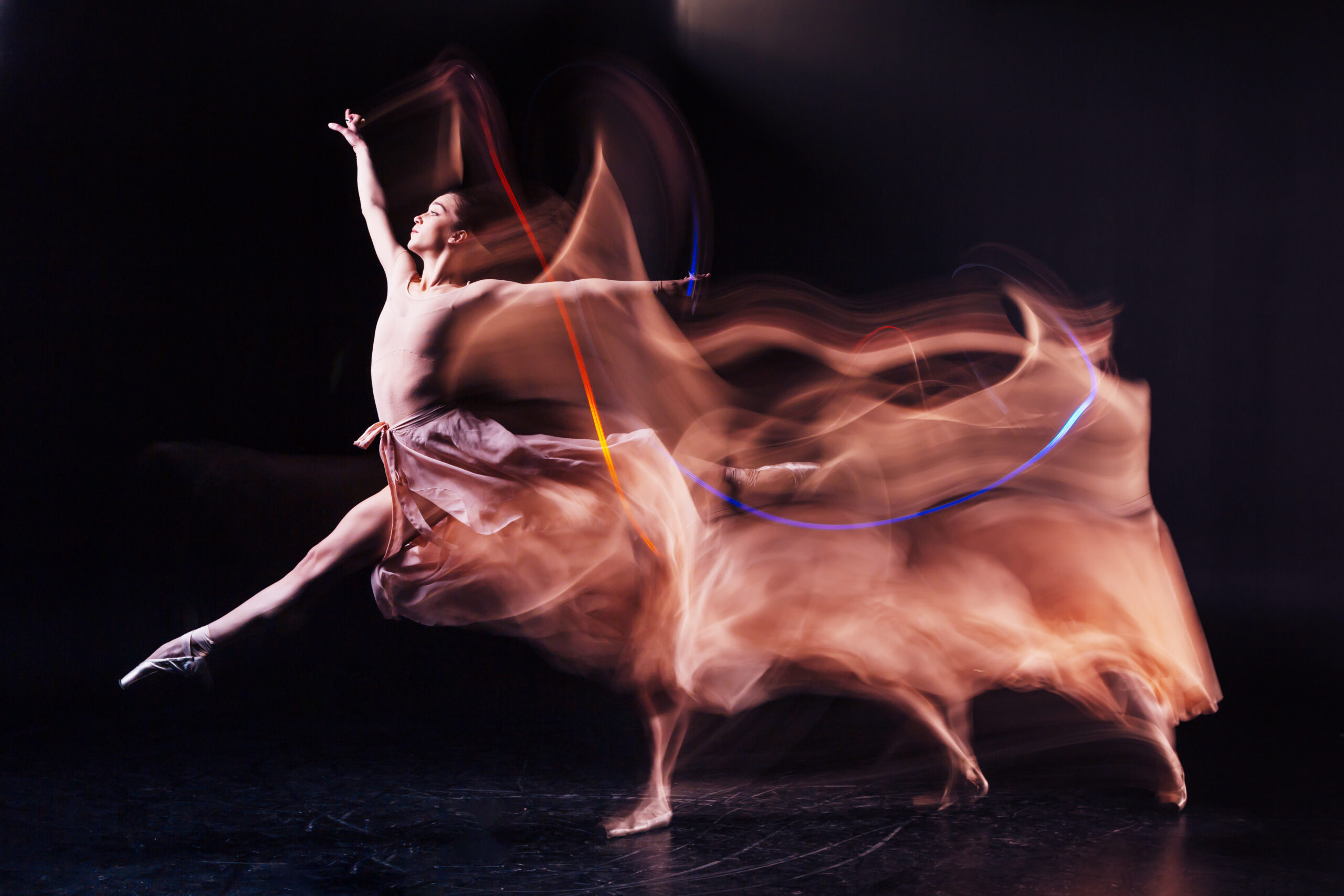 Ballet dancer leaping with the light blurred behind in a fiery orange tone.