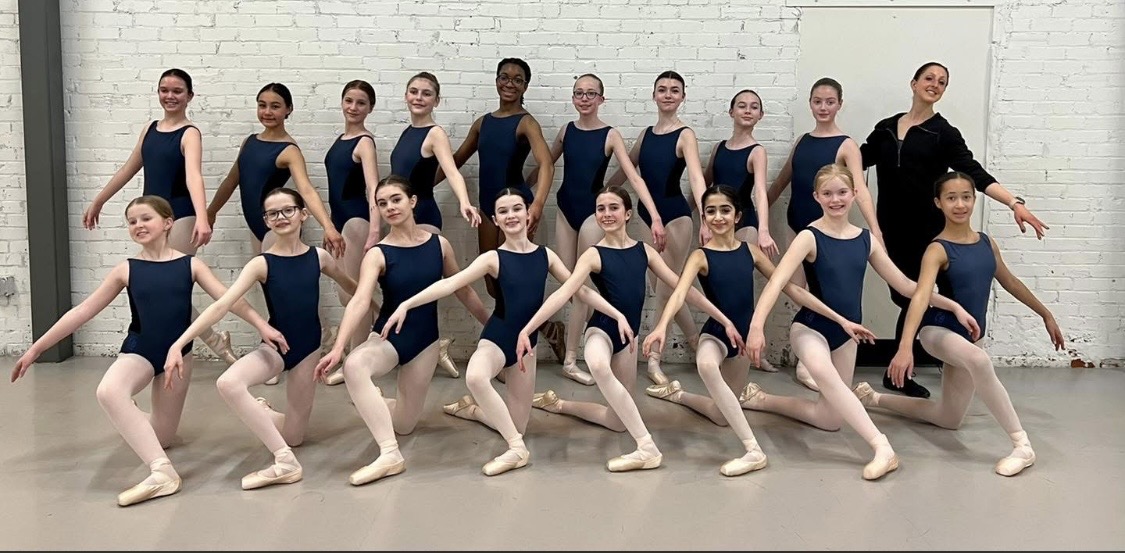 Sandre poses with her students who stand in two lines, the top line standing while the bottom line kneels.