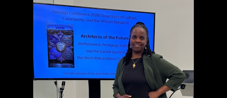 Dr. Andrea Markus standing in front of a presentation slide wearing a dress and blazer.
